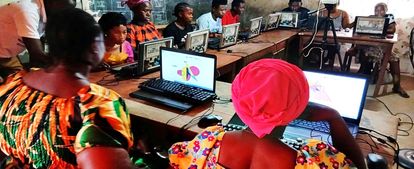 Women and youth learning graphic design on laptops at a community learning centre