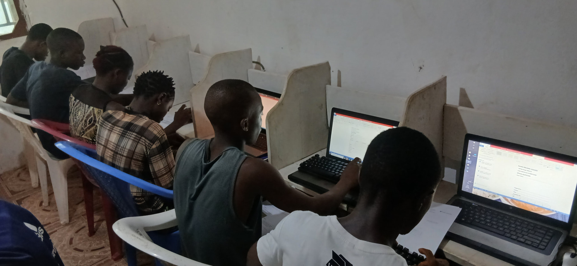 Learners seated in a row of booths typing documents on laptops