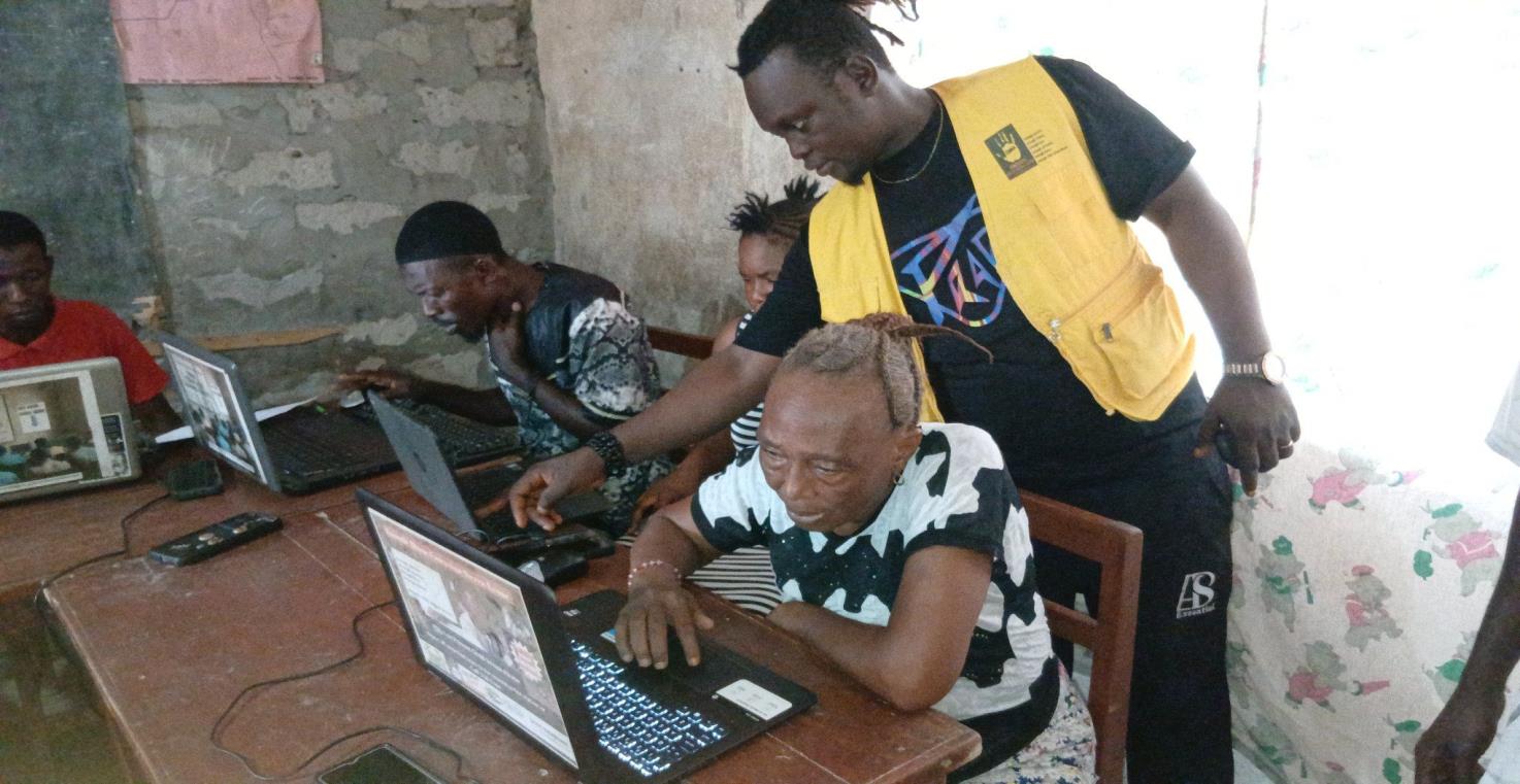 An instructor assisting an adult learner with digital literacy on a laptop