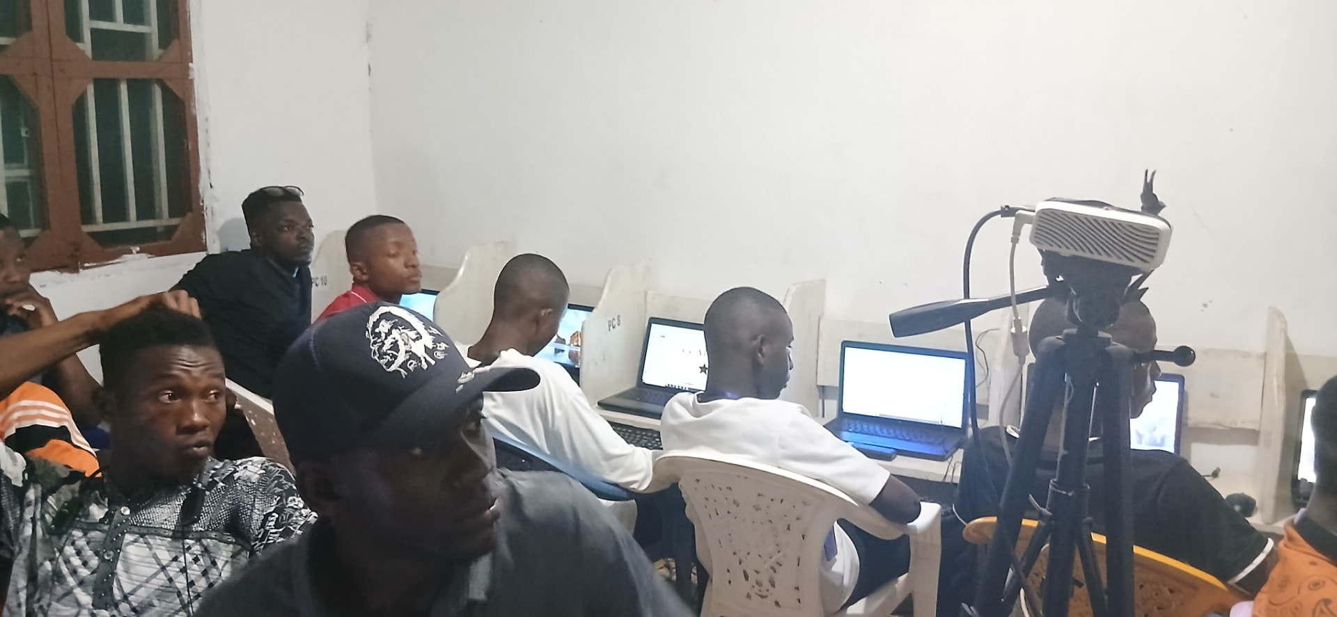 Community members seated at laptops attending an evening ICT training session